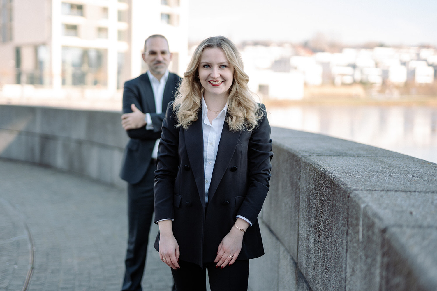 Fotograf Ahaus porträtiert Businessfrau im Anzug vor moderner Stadt-Kulisse.
